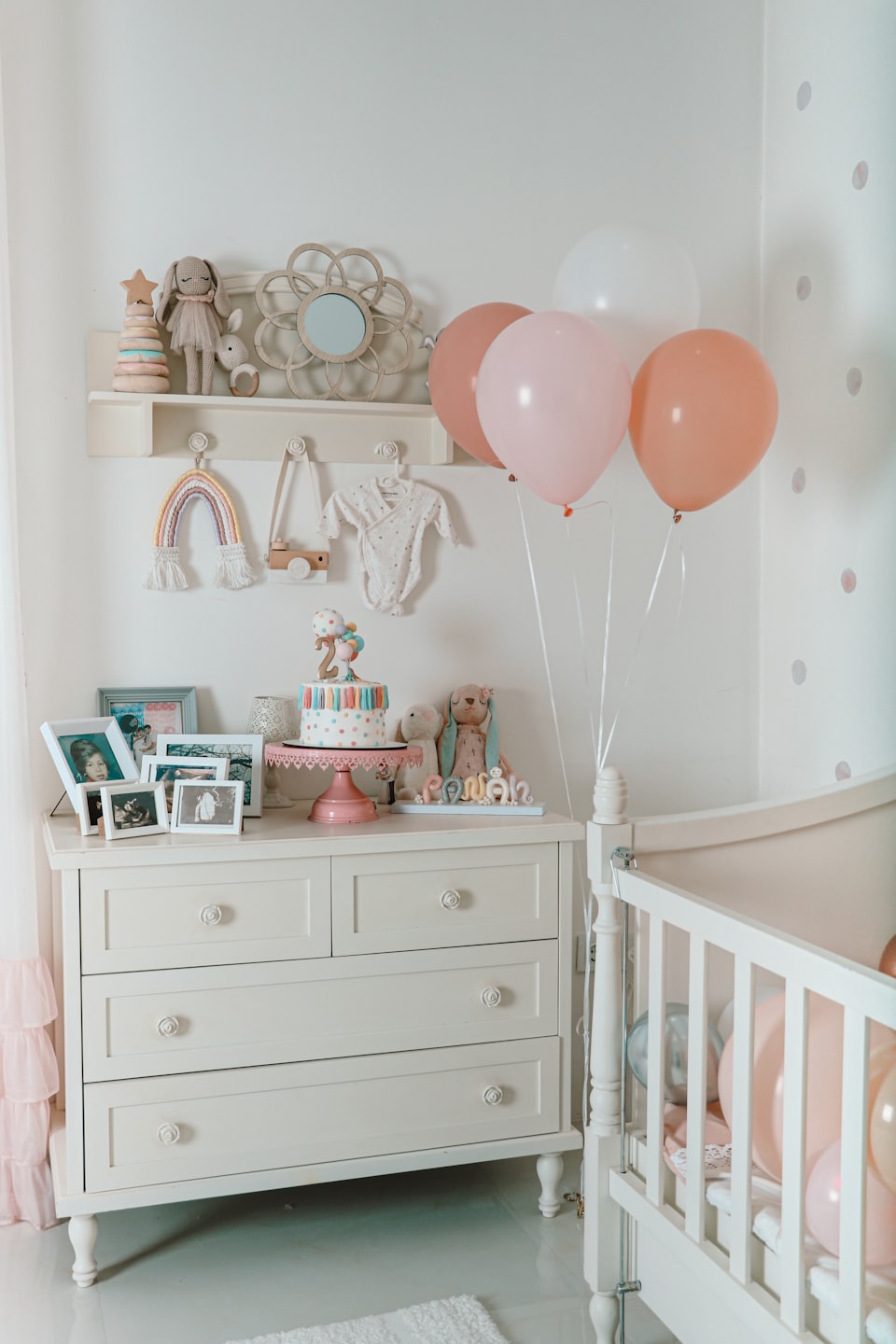 Second birthday decorations on a dresser with cake and balloons.