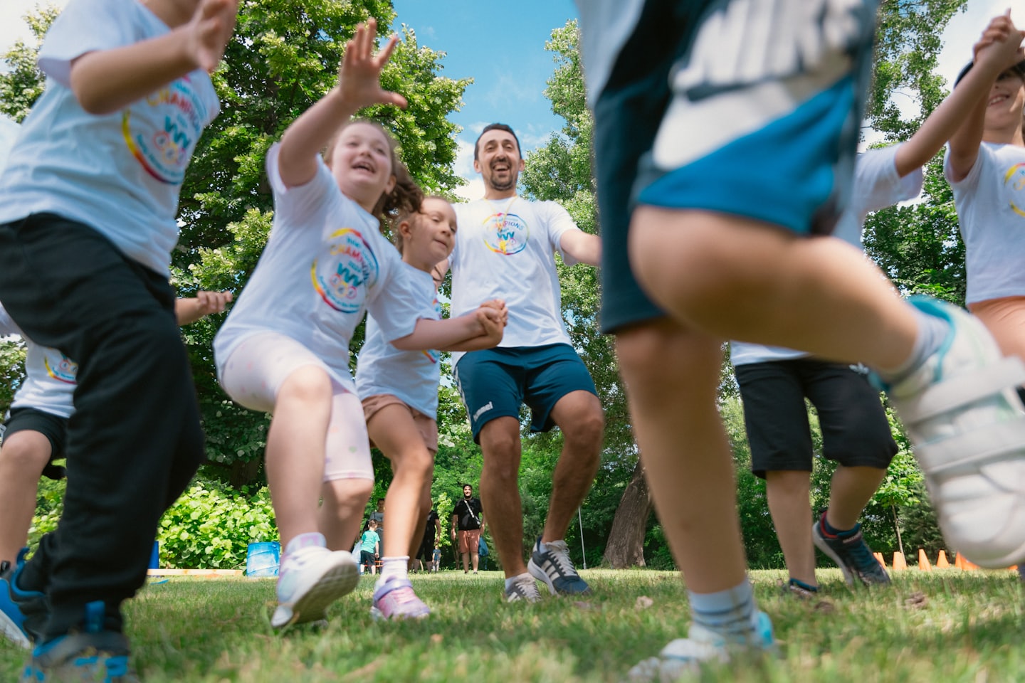 A group of people wearing white shirts jumping in a park.