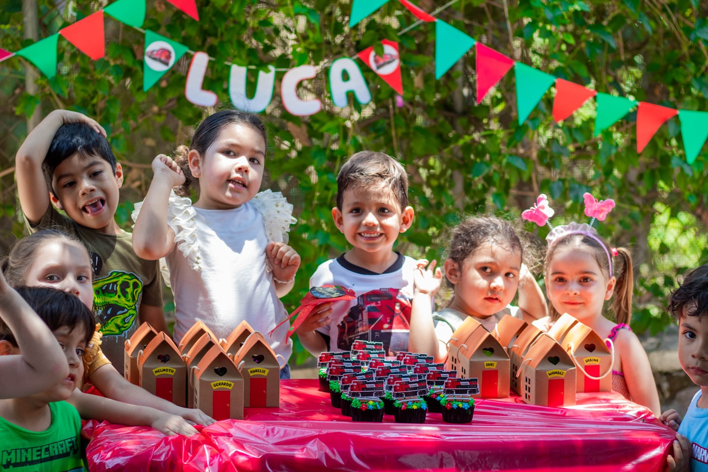 Children celebrating at a party with cupcakes and gift boxes.