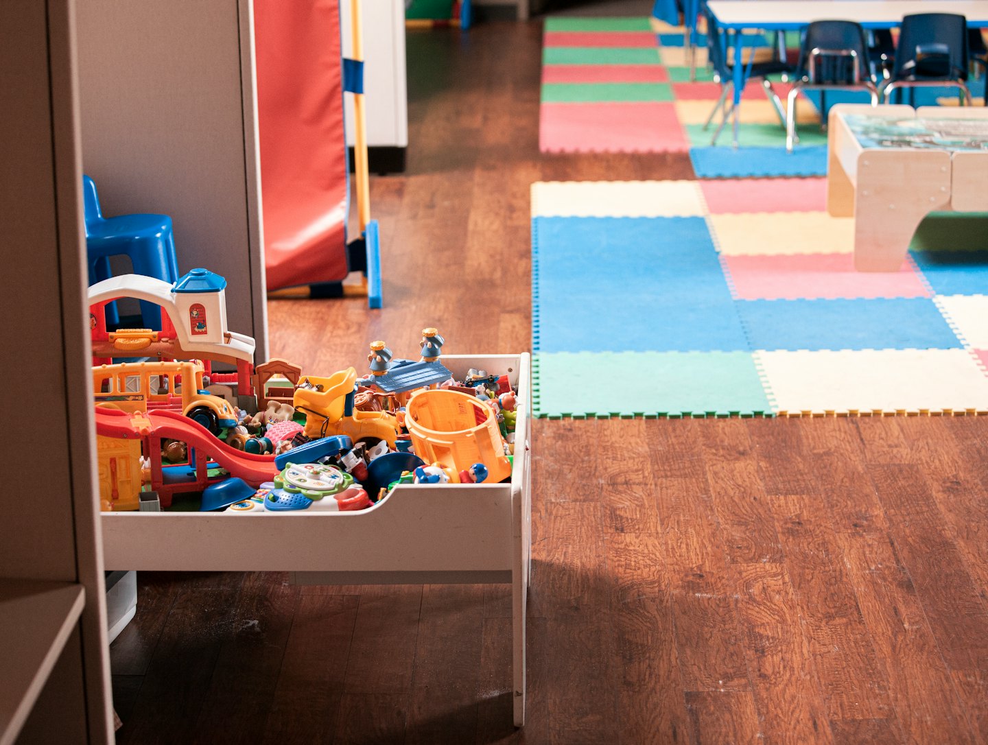 Toy bin overflowing with colorful children's toys in a playroom.