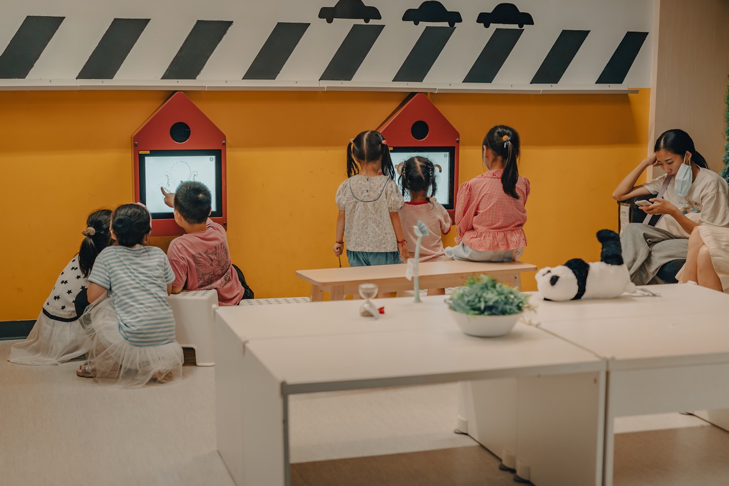 Children play games on digital screens in an indoor center.