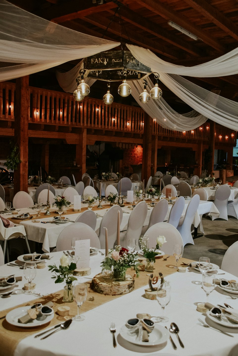 Decorated tables with floral arrangements and string lights for a rustic event.
